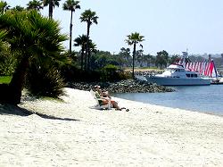 couple sitting on the beach in front of yacht