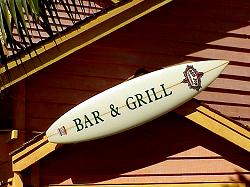 bar and grill sign on surfboard on wall